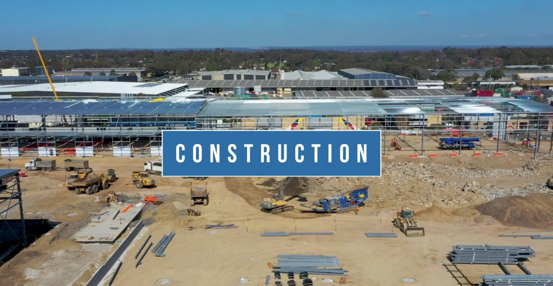 Aerial view of large commercial construction site with machinery, steel framing and “Construction” title overlay.