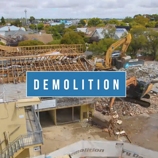 A time-lapse image capturing the demolition of a structure at a construction site, with debris falling and machinery in action.
