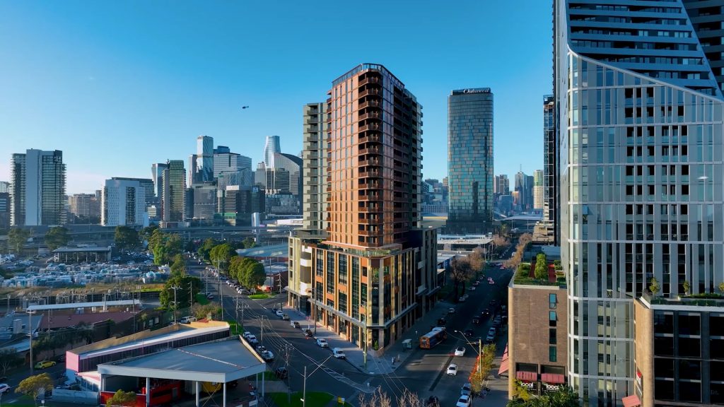 Daytime inner‑city view with mid‑rise brown residential tower on street corner, surrounded by offices, roads and green spaces.